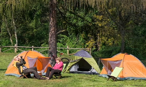 Camping tents set up on green hillside with people relaxing